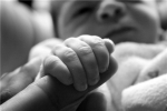 In this photograph, a newborn is grasping onto a parent's finger.